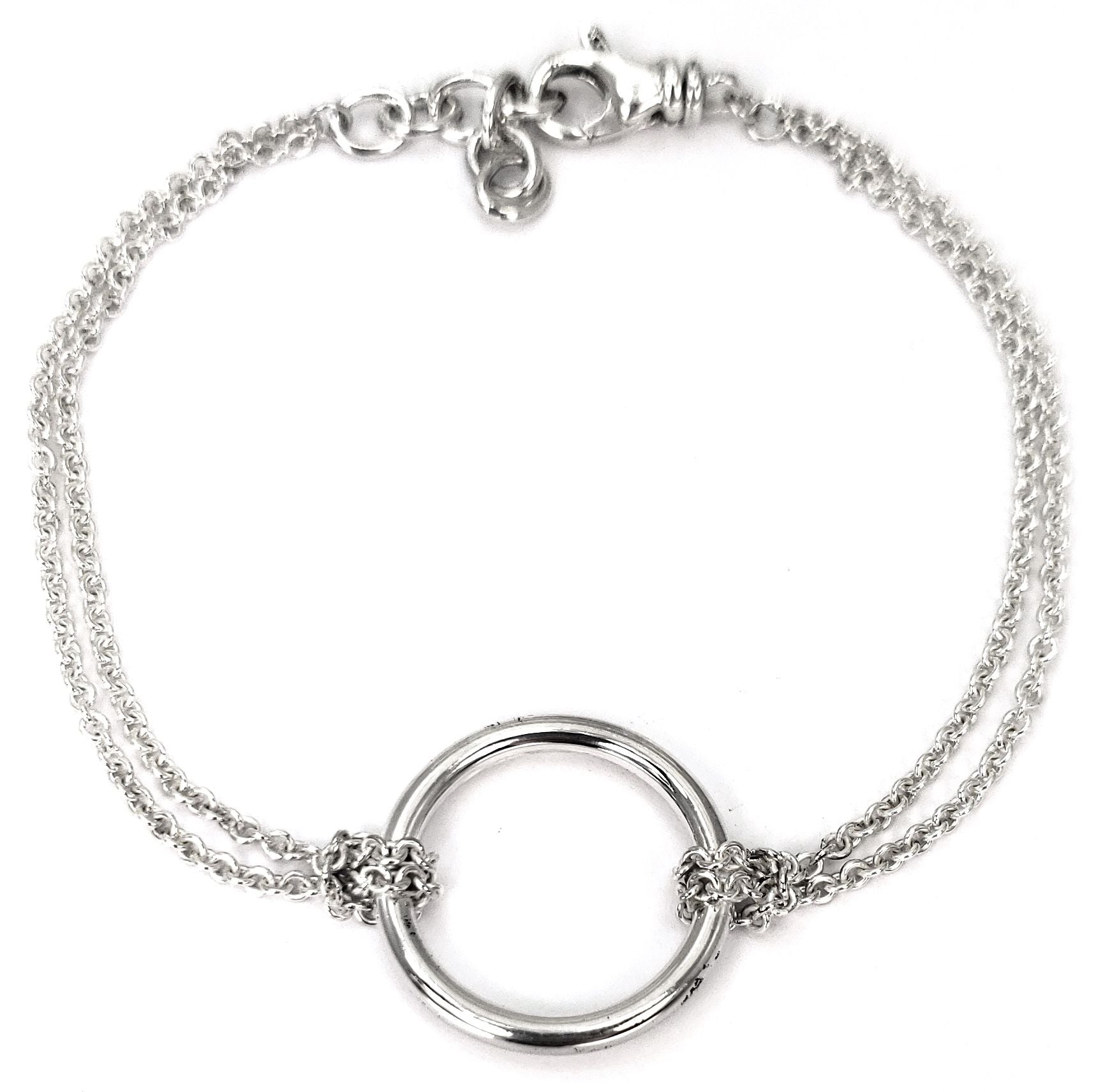 Silver bracelet with two thin machine-made chains and a polished ring in the middle.